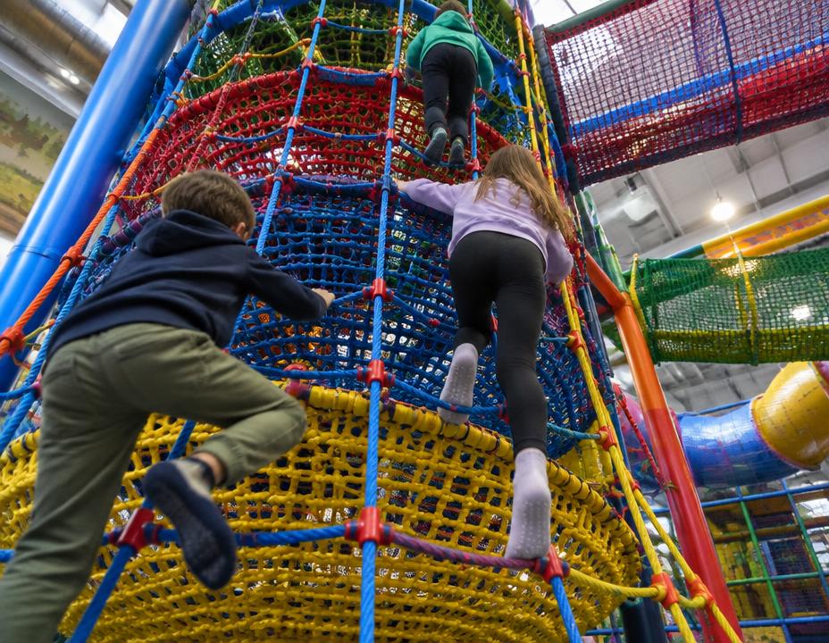 Kinder klettern an einem bunten Netz-Kletterturm